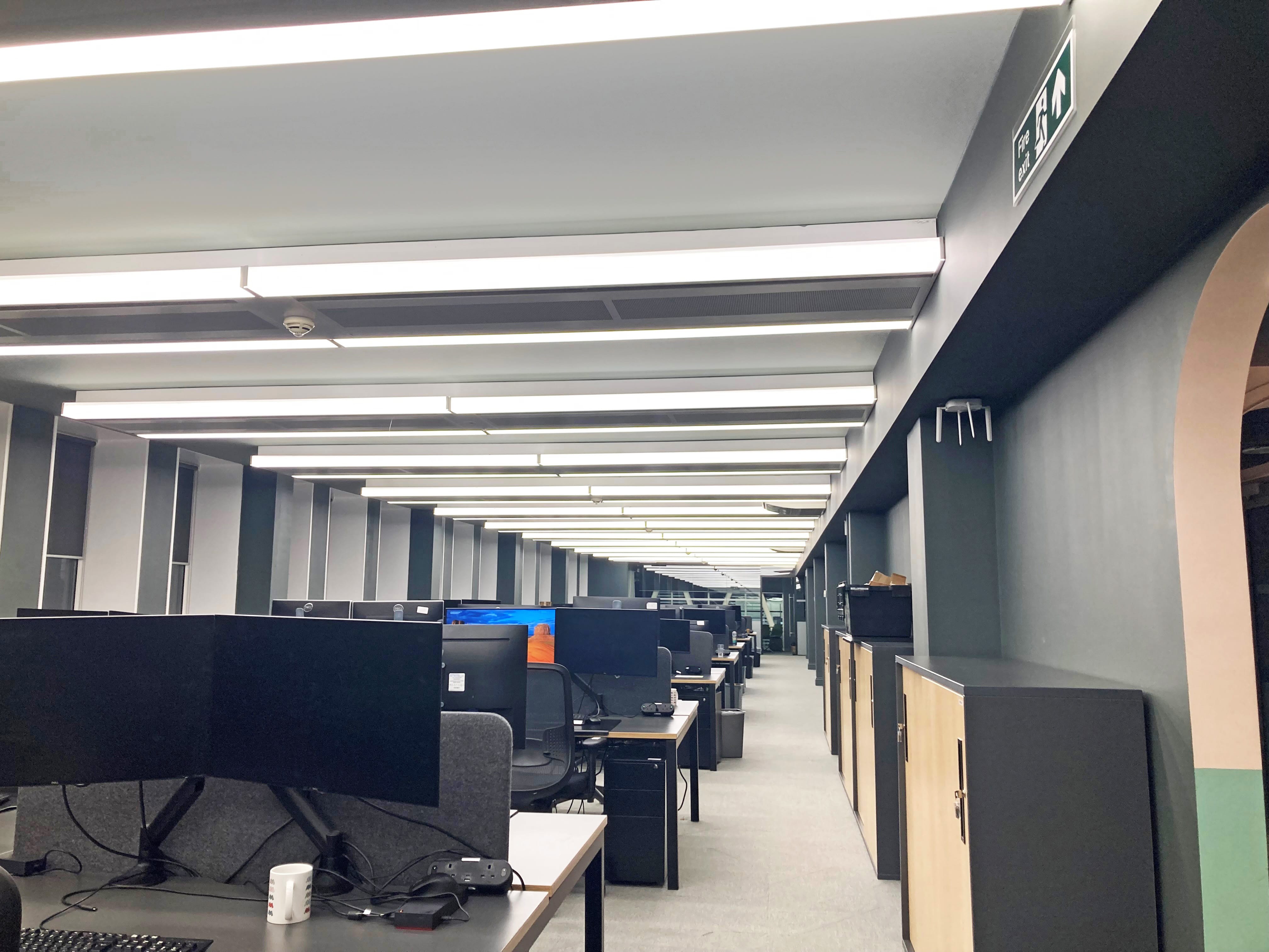 65 Southwark Street Office, filled with desks topped with computers; radiant panels are fitted all along the ceiling